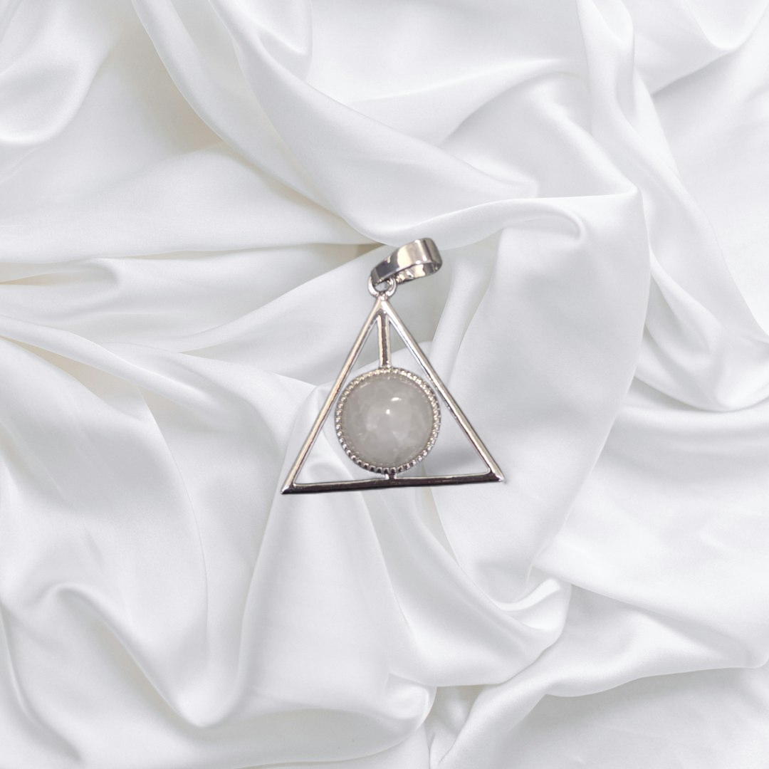 Triangular pendant with a central gemstone on a white fabric background