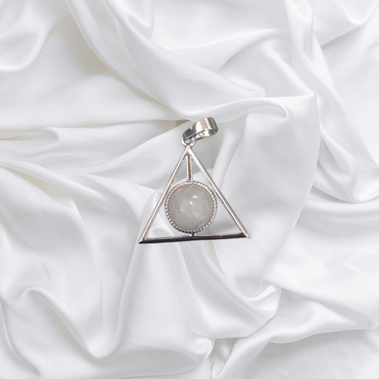 Triangular pendant with a central gemstone on a white fabric background